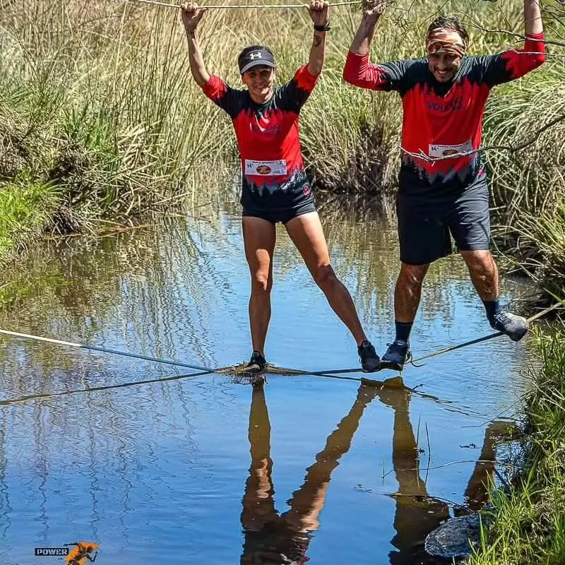 Dos participantes cruzando la cañada tomados de la mano sobre el agua