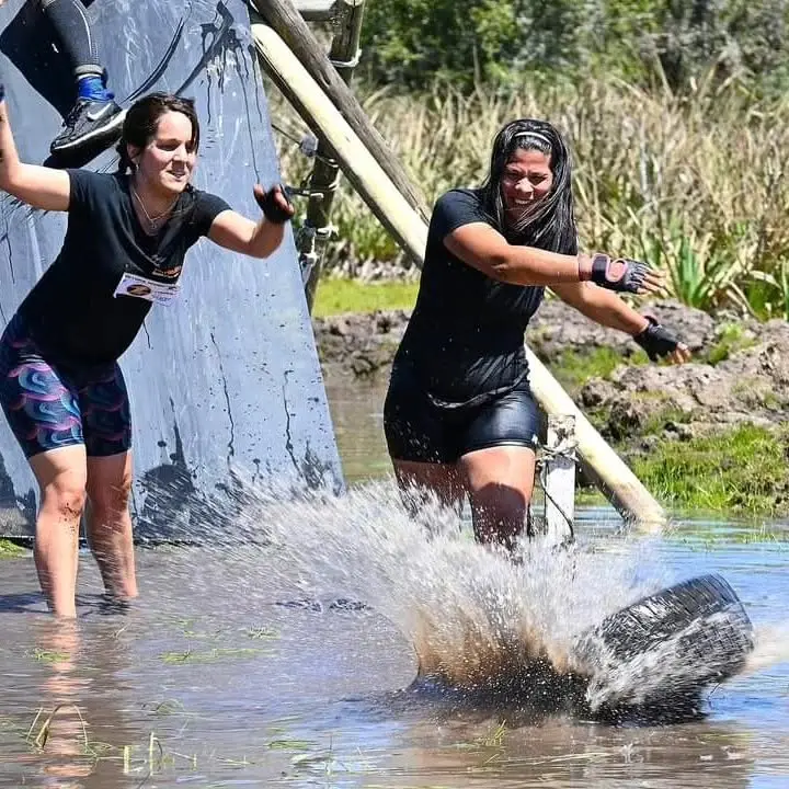 Dos participantes cruzando la cañada agarradas de una cuerda