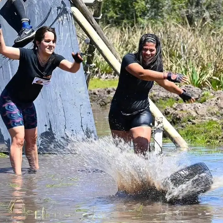 Dos participantes cruzando la cañada agarradas de una cuerda
