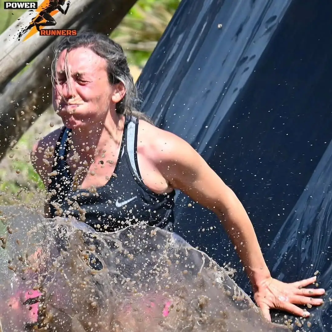 Participante saliendo del pozo de barro con esfuerzo