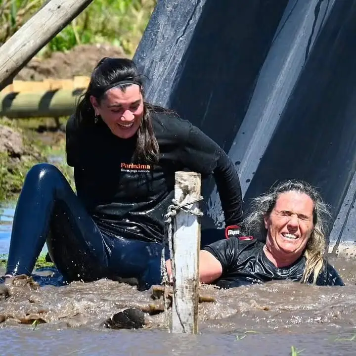 Dos participantes bajando juntos por el tobogán de barro