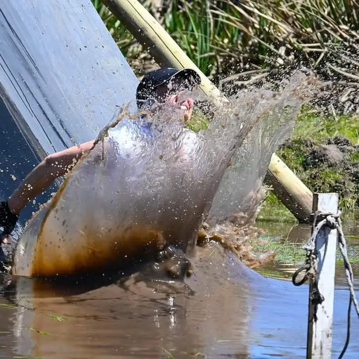 Participante levantando una ola de agua al caer del tobogán