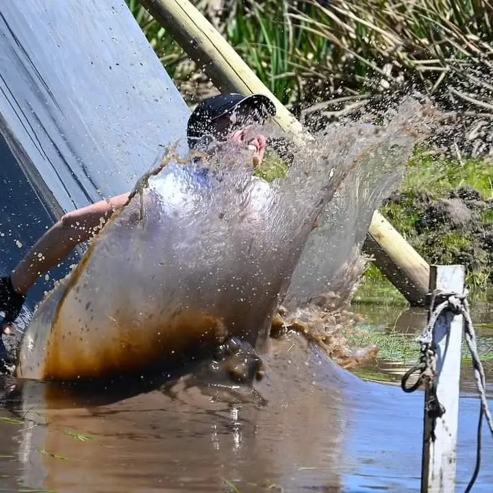 Participante levantando una ola de agua al caer del tobogán